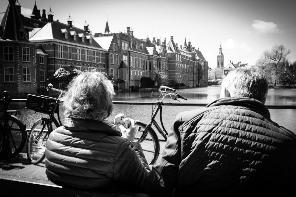 Two people on a bench having lunch overlooking Buitenhof water. Black and white.