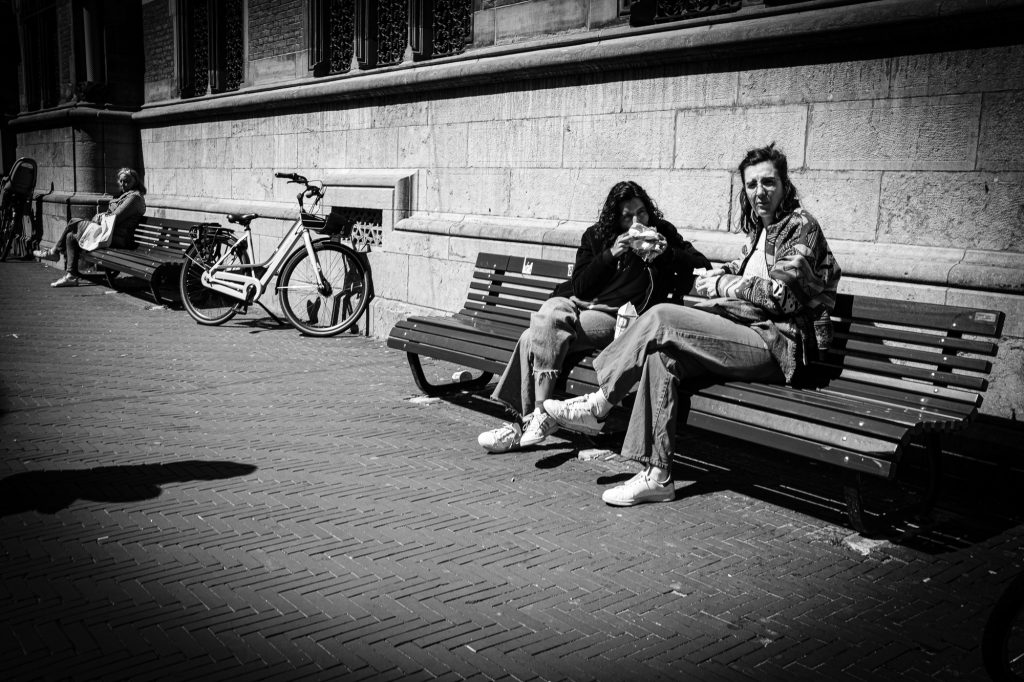 Two girls having lunch in a bench on Lange Poten. Black and white